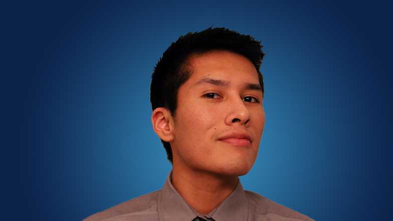 Student Justin Billy smiling with a blue background