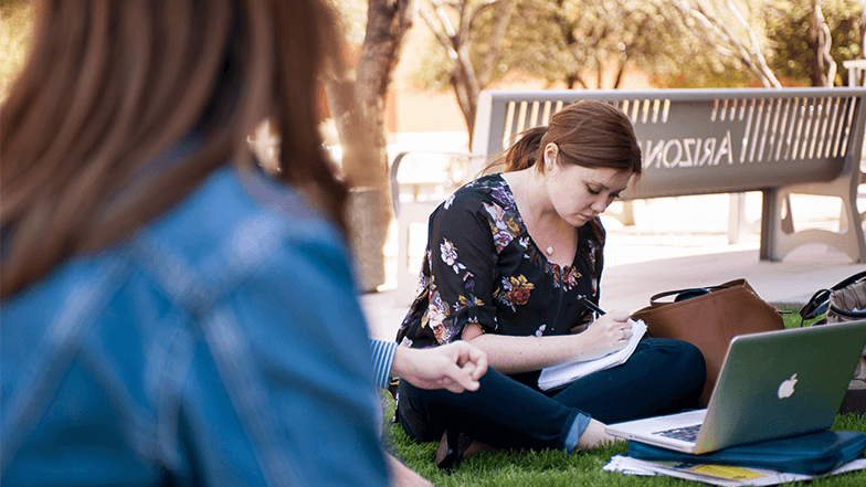 Two students studying in the grass at the University of Arizona