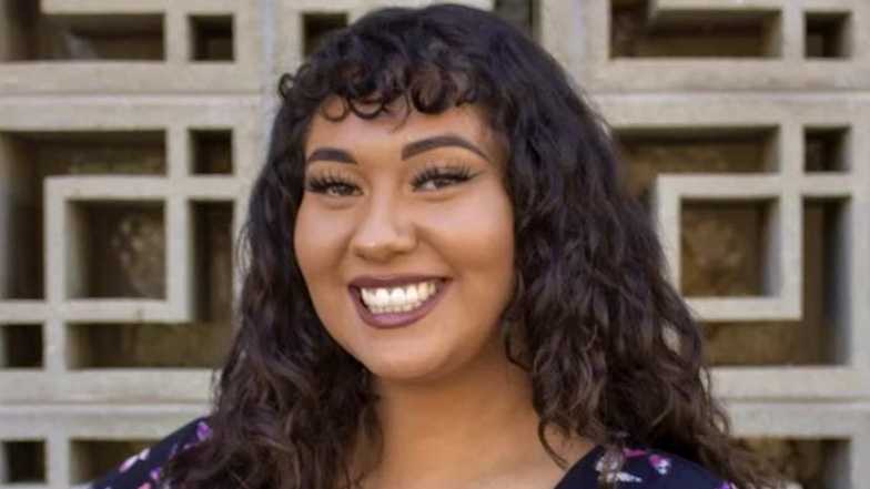 Student Nadira Sage Mitchell smiling in front of abstract background