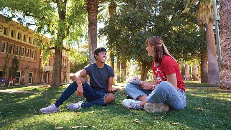 Two students sitting on the grass on campus