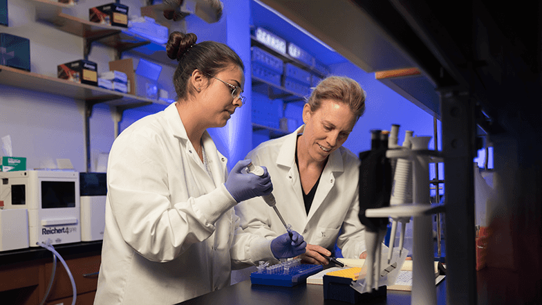 A student and professor in white lab coats