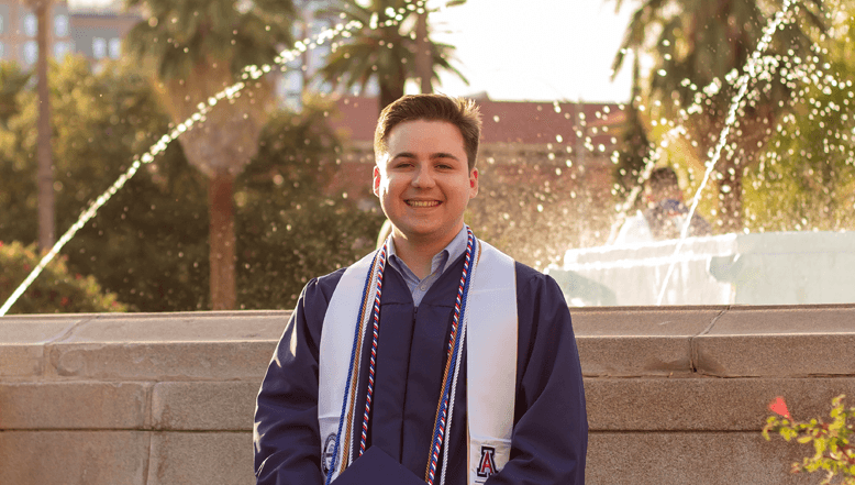 Andrew in his graduation gown with sashes and cords